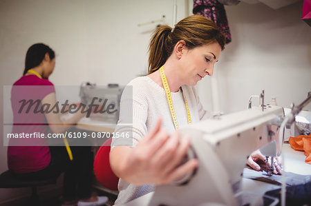 Female dressmaker sewing on the sewing machine in the studio