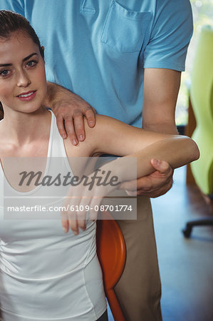 Portrait of physiotherapist stretching arm of a female patient in the clinic