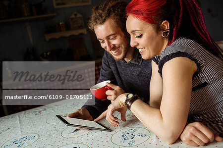 Young happy couple using digital tablet while relaxing on bed at home