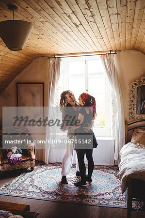 Full length of young couple dancing against window at home