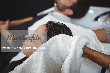 Hair stylist drying woman hair with towel in salon