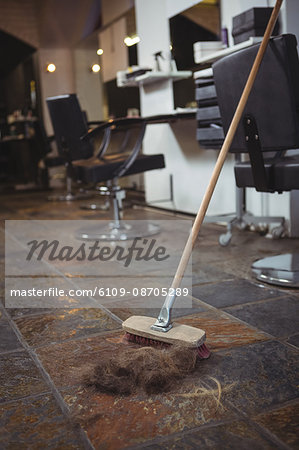 Hair waste on floor with a broom in salon