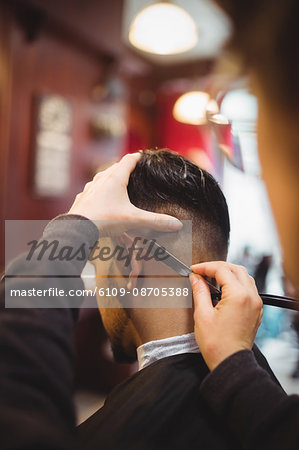 Man getting his hair trimmed with razor in barber shop