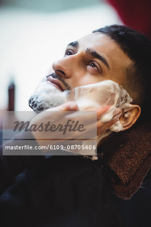 Man getting his beard shaved in barber shop