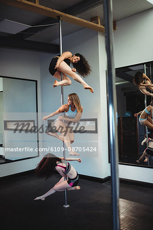 Pole dancers practicing pole dance in fitness studio