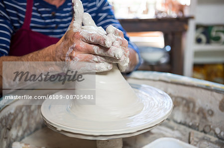 Mid section of potter making pot in pottery workshop