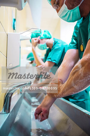 Group of surgeons washing their hands at washbasin in hospital
