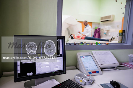 Digital brain scan on computer monitor with MRI scanner in background