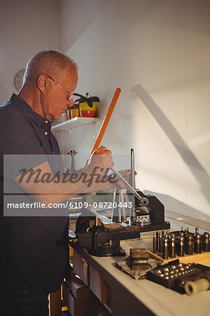 Focused goldsmith using mini drill press in workshop
