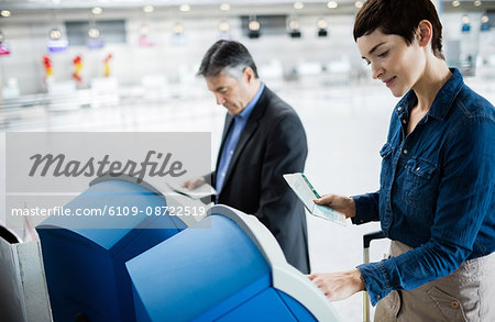 Business people using self service check-in machine at airport