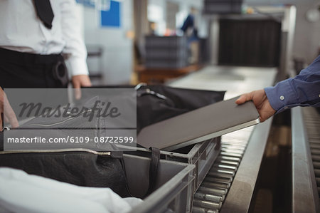 Man putting laptop into tray for security check at airport