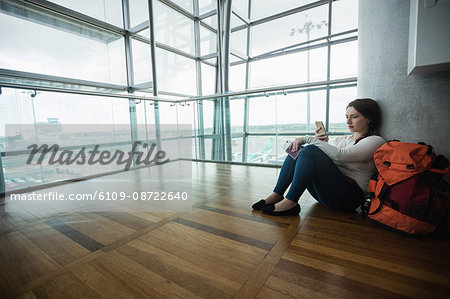 Woman listening to music on mobile phone while sitting in waiting area