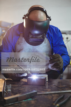 Male welder working on a piece of metal in workshop