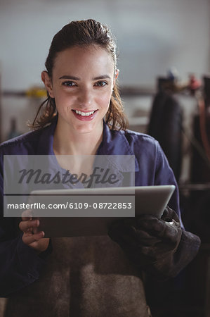 Portrait of female welder holding digital tablet in workshop