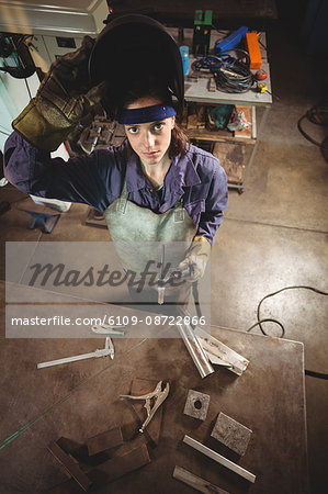 Female welder holding welding torch in workshop