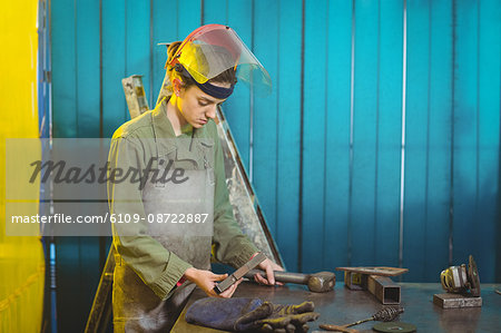 Female welder examining a piece of metal in workshop