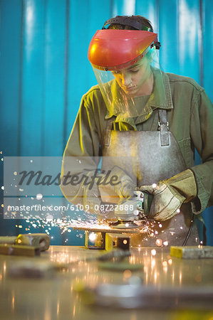 Female welder using circular saw in workshop