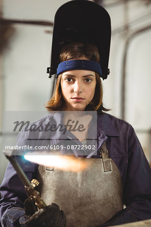 Female welder holding welding torch in workshop