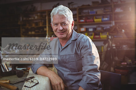 Portrait of smiling shoemaker sitting in workshop