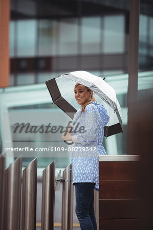 Beautiful woman holding umbrella and standing on street during rainy season