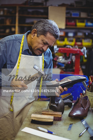 Shoemaker hammering on a shoe in workshop