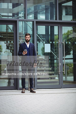 Businessman using mobile phone outside office