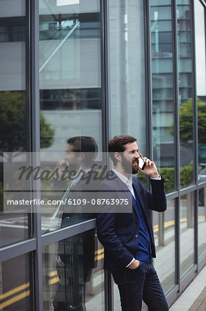 Businessman talking on mobile phone outside office