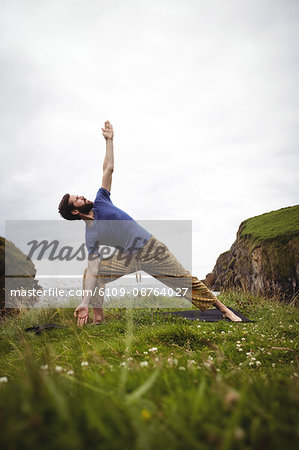 Man performing stretching exercise on cliff