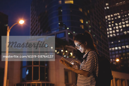 Young woman using digital tablet on street at night