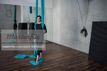 Gymnast holding fabric rope in fitness studio