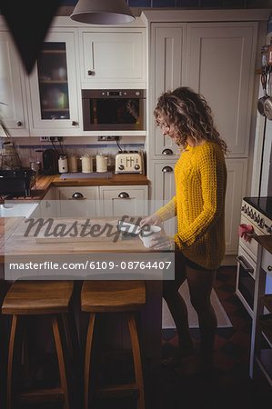 Beautiful woman using digital tablet while having coffee in kitchen at home