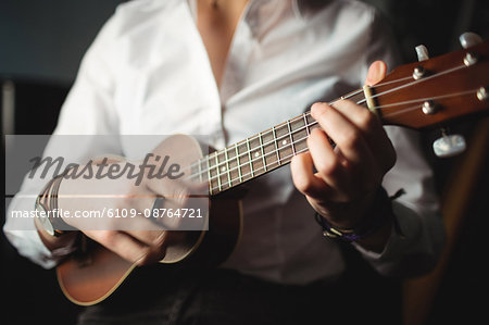 Mid-section of woman playing a guitar in music school