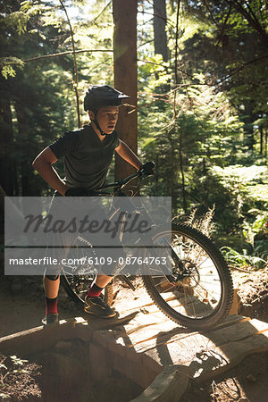 Male cyclist walking with mountain bike in forest
