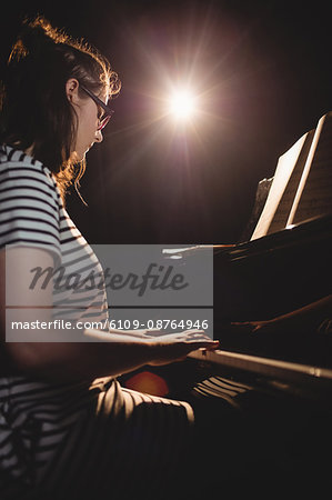 Female student playing piano in a studio