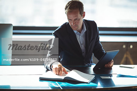 Businessman checking his diary while using digital tablet in office