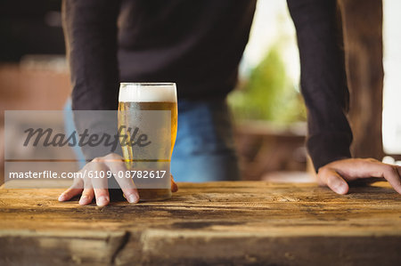 Mid section of man with glass of beer at bar