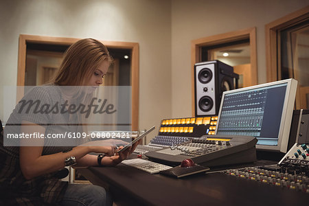 Audio engineer using digital tablet in recording studio