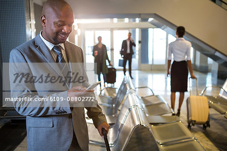 Businessman using mobile phone in waiting area at airport terminal