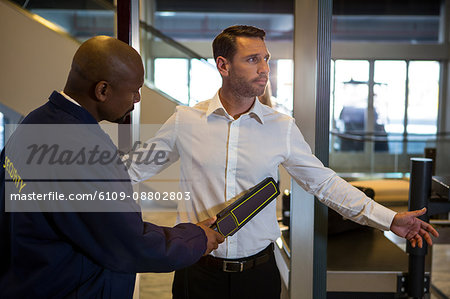 Security guard frisking a passenger at airport terminal