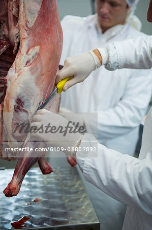 Butchers cutting meat at meat factory