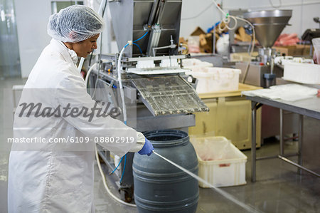 Female butcher cleaning the floor at meat factory