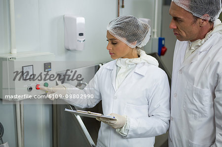 Butchers maintaining records on clipboard at meat factory