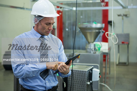 Attentive technician using digital tablet at meat factory