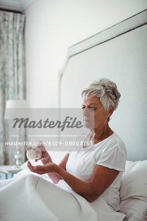 Senior woman taking medicine in bedroom at home