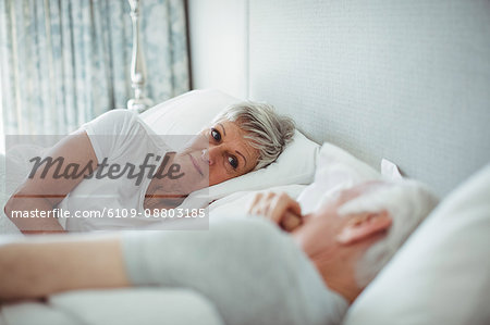 Senior couple lying on bed in bedroom