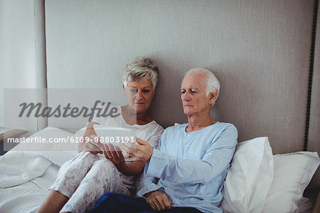 Senior couple using digital tablet on bed in bed room