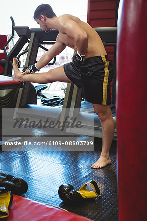 Boxer doing stretching exercise in fitness studio