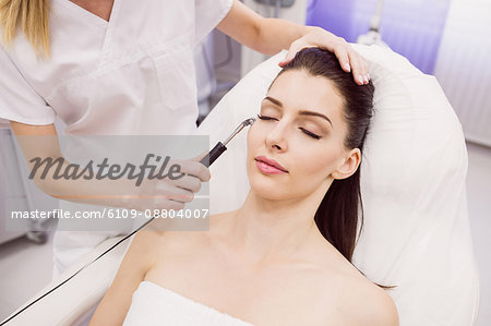 Dermatologist performing laser hair removal on patient face in clinic