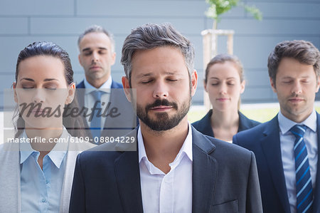 Group of business people with eyes closed standing outside office building