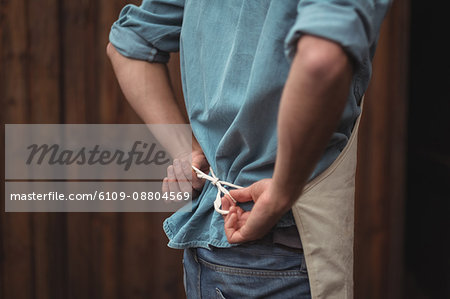 Mid section of man wearing apron at home brewery